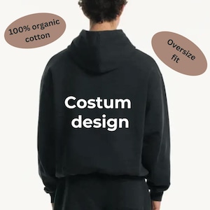 May include: Black hooded sweatshirt with the text "Costum design" printed on the back. The sweatshirt is made from 100% organic cotton and has an oversized fit.