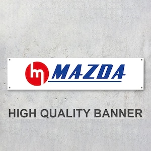 Op de afbeelding: Witte banner met het Mazda-logo in blauw en rood. Het logo bevat het Mazda-woordmerk en een gestileerde "M" in een rode cirkel. De tekst "HIGH QUALITY BANNER" is onder het logo gedrukt.