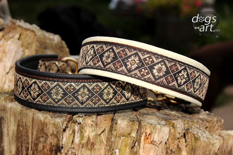Puede incluir: Dos collares para perros con base de cuero negro y ribete con estampado marr&oacute;n y dorado. Los collares est&aacute;n sobre una superficie de madera.
