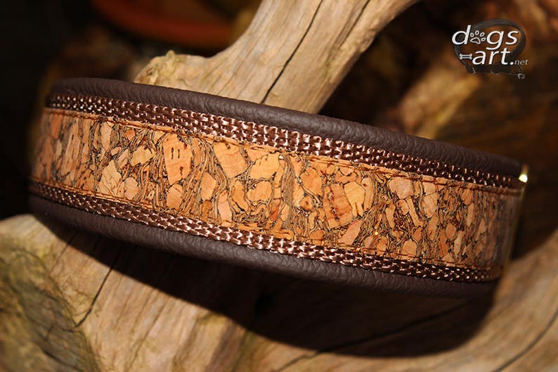 May include: A brown leather dog collar with a cork inlay and a brown stitched border. The collar has a gold metal buckle.