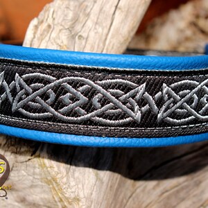 May include: A black leather dog collar with a blue edge and a silver and black Celtic knot design.