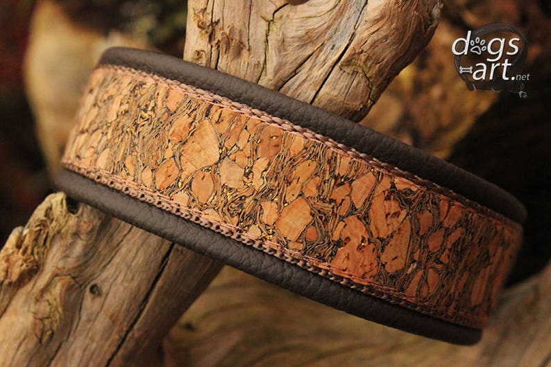 May include: A brown leather dog collar with a cork and gold accent. The collar has a brown leather strap with a cork and gold accent.