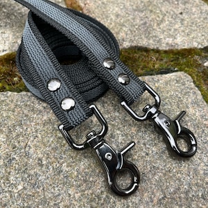 May include: A black and gray striped dog leash with two black metal clips.