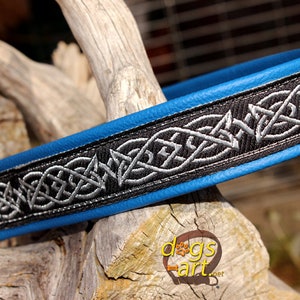 May include: A blue leather dog collar with a black and silver Celtic knot design. The collar has a silver D-ring.