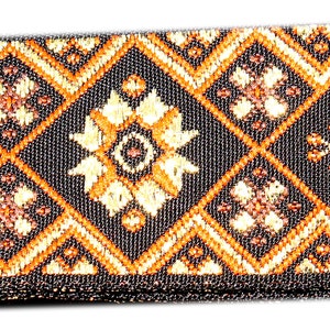 May include: Black and gold patterned fabric ribbon with a geometric design. The ribbon has a black border and a repeating pattern of diamond shapes with floral motifs.