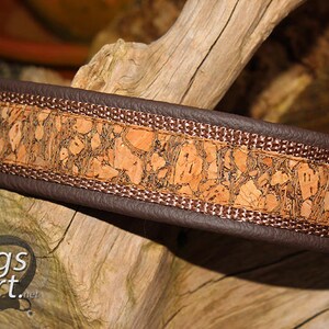 May include: A brown leather dog collar with a cork and brown fabric trim. The collar has a decorative pattern of cork pieces.