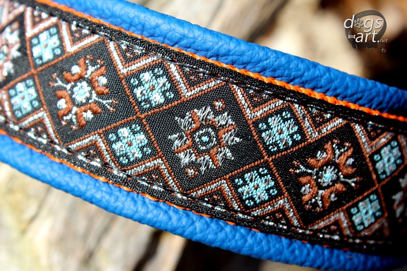 May include: A blue leather dog collar with orange stitching and a black and brown patterned fabric trim. The fabric trim features a geometric design with blue, silver, and brown accents.