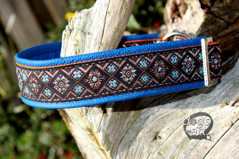 May include: A blue leather dog collar with a black and brown patterned trim. The collar has a silver buckle and is decorated with a geometric design.