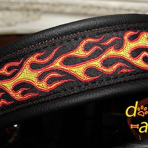 May include: Black leather dog collar with a red and yellow flame design. The collar is stitched with a black thread and has a smooth leather finish.