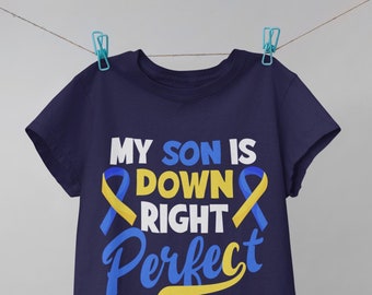 May include: Navy blue t-shirt with a white graphic that reads "My son is down right perfect" with yellow and blue ribbon symbols. The text "#downsyndromeawareness" is printed below the graphic.