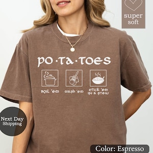May include: Espresso-colored t-shirt with the word "POTATOES" in white, along with three illustrated cooking steps. The shirt has a crew neck and short sleeves. The text "super soft" is in the upper right corner.