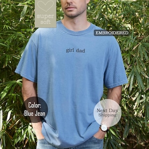 K&ouml;nnte beinhalten: Ein T-Shirt in Jeansblau mit dem gestickten Text "girl dad" auf der Vorderseite. Das Shirt ist super weich und bequem.
