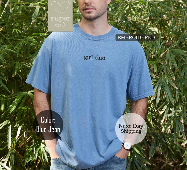 K&ouml;nnte beinhalten: Ein T-Shirt in Jeansblau mit dem gestickten Text "girl dad" auf der Vorderseite. Das Shirt ist super weich und bequem.