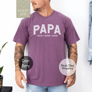 May include: A purple t-shirt with the word "PAPA" in white outlined letters. The names Lucas, Olivia, and David are printed below the word "PAPA".