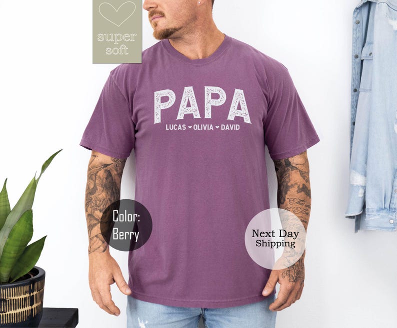 May include: A purple t-shirt with the word "PAPA" in white outlined letters. The names Lucas, Olivia, and David are printed below the word "PAPA".