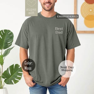 K&ouml;nnte beinhalten: Ein moosgr&uuml;nes T-Shirt mit dem gestickten Text "Best Dad" auf der Vorderseite. Das Shirt ist super weich und der Versand erfolgt am n&auml;chsten Tag.