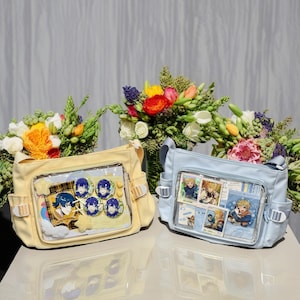 May include: Two canvas bags with clear plastic windows. The yellow bag has blue and yellow character pins inside. The blue bag has colorful photos inside. Both bags have adjustable straps.