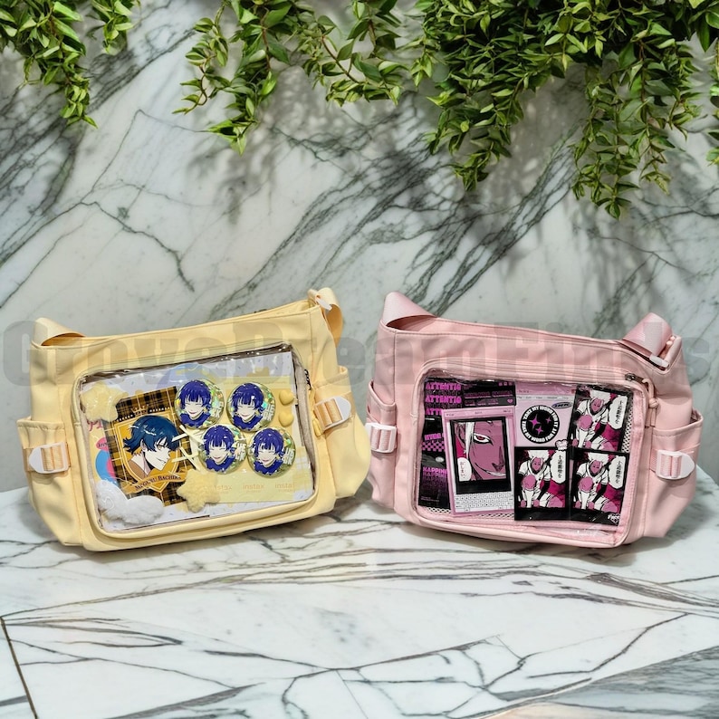 May include: Two canvas shoulder bags with clear plastic front pockets. The yellow bag has anime character pins and a plaid pattern inside. The pink bag has a black and white graphic print inside.