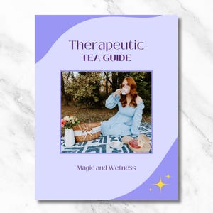 May include: A purple and white guide with the text "Therapeutic Tea Guide" and "Magic and Wellness". The guide features a photo of a person in a blue dress sitting on a blanket in a forest setting, holding a cup of tea.