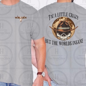 May include: Light gray t-shirt with the word "WALLEN" and a skull graphic on the front. The back of the shirt features a skull wearing a cowboy hat over a globe, with the text "I'M A LITTLE CRAZY BUT THE WORLDS INSANE."