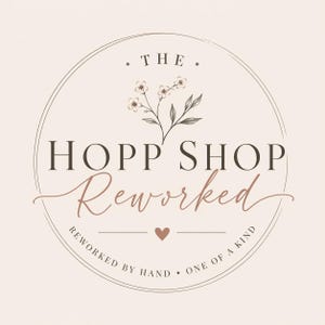 May include: A circular logo with the text "THE" at the top, and "HOPP SHOP" in a serif font. Below, the word "Reworked" is in a cursive font. The logo includes a floral illustration and the text "REWORKED BY HAND &bull; ONE OF A KIND".