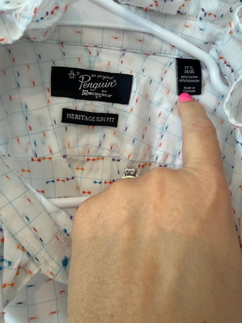 May include: White button-down shirt with a grid pattern and colorful accents. The shirt features the "Penguin" logo and "Heritage Slim Fit" label. The tag indicates a size of 17 1/2 and 34/35, made of 60% cotton and 40% polyester.