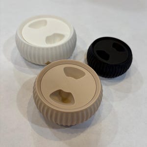 May include: Three round, ceramic pet food bowls with a ribbed design. The bowls are in white, beige, and black.