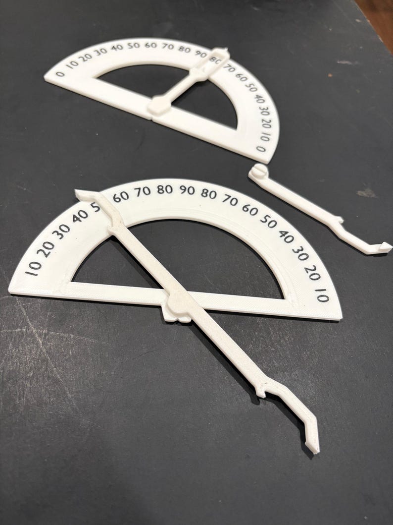 K&ouml;nnte beinhalten: Zwei wei&szlig;e Kunststoff-Geodreiecke mit schwarzen Markierungen. Die Geodreiecke sind in Grad von 0 bis 90 gekennzeichnet. Die Geodreiecke sind zum Messen von Winkeln bestimmt.