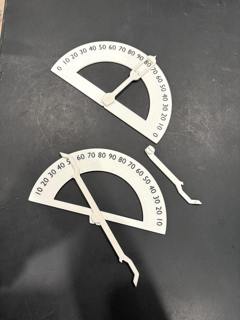 K&ouml;nnte beinhalten: Zwei wei&szlig;e Kunststoff-Geodreiecke mit schwarzen Markierungen. Die Geodreiecke sind in Grad von 0 bis 90 gekennzeichnet. Die Geodreiecke werden zum Messen von Winkeln verwendet.