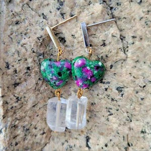 May include: A pair of earrings with green and pink heart-shaped stones and clear crystal accents.