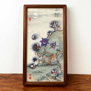 Puede incluir: Una pintura de acuarela enmarcada que presenta un paisaje con personajes de fantasmas de dibujos animados. La obra de arte tiene un estilo asiático tradicional con una luna llena, montañas y una cascada. El marco es de madera oscura.