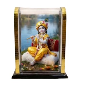 Op de afbeelding: Een decoratieve ingelijste afbeelding met een figuur in gele kleding die een fluit bespeelt. De figuur zit op een wit kussen met een rood kussen, omringd door kleine olielampen. De lijst heeft een gouden mozaïekrand en een zwarte basis.