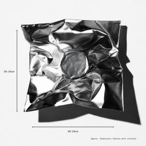 May include: A square, metallic silver bowl with a highly reflective, crinkled surface texture. The bowl features a central circular depression and irregular folds throughout. Text indicates dimensions of 20-24 cm, noting they vary with the crinkle.