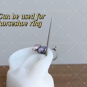 May include: A close-up of a silver horseshoe ring with a clear gem on one end. The ring is on a white display stand. The text "Can be used for horseshoe ring" is visible at the top of the image.