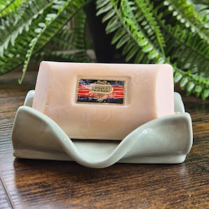 May include: A set of three ceramic mugs with a speckled, matte finish in cream, light grey, and dark grey. Each mug has a simple, minimalist design and a rounded handle.