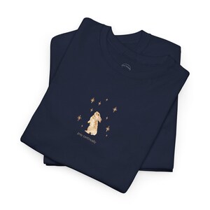 May include: Navy blue t-shirt with a small illustration of a brown rabbit standing on its hind legs with its paws raised. The rabbit is surrounded by gold stars. The text "pray continually" is printed below the rabbit.
