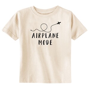 Puede incluir: Camiseta color crema con las palabras "AIRPLANE MODE" en negro, acompa&ntilde;ada de una l&iacute;nea de puntos y un peque&ntilde;o gr&aacute;fico de avi&oacute;n. La camiseta es de material suave y tiene cuello redondo.