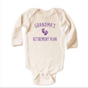 Peut inclure: Un body b&eacute;b&eacute; &agrave; manches longues de couleur cr&egrave;me avec le texte "Grandma's Retirement Plan" et un graphique de traces de pas violet avec un c&oelig;ur dans chaque empreinte.