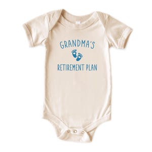 Peut inclure: Un body b&eacute;b&eacute; &agrave; manches courtes de couleur cr&egrave;me avec un motif bleu qui dit "Grandma's Retirement Plan" avec une paire d'empreintes de pieds bleues.