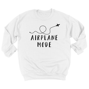Puede incluir: Sudadera blanca con la frase "AIRPLANE MODE" en negro, acompa&ntilde;ada de una l&iacute;nea de puntos y un avi&oacute;n. El dise&ntilde;o sugiere viajes o un estado de relajaci&oacute;n.
