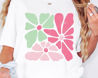 May include: White t-shirt with a graphic of pink and green flowers. The flowers have a distressed, vintage look.