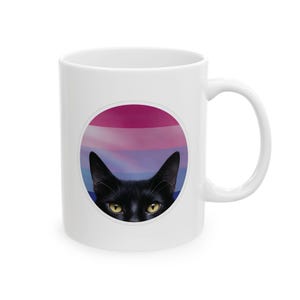 Puede incluir: Taza de cerámica blanca con un gato negro asomándose detrás de un círculo con un diseño de bandera del orgullo bisexual.