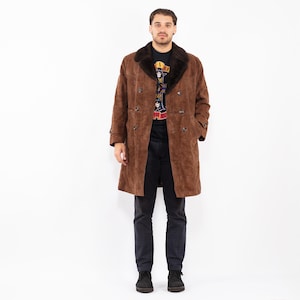 Könnte beinhalten: Ein brauner Wildledermantel mit einem dunkelbraunen Kunstfellkragen. Der Mantel hat ein doppelreihiges Design mit mehreren Knöpfen. Die Person trägt ein schwarzes T-Shirt und eine schwarze Hose. Der Mantel ist knielang.