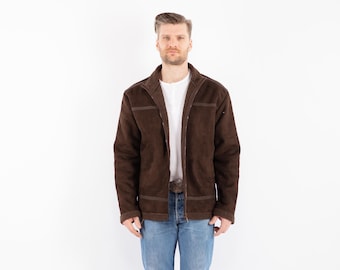 Puede incluir: Una chaqueta de ante marrón con cierre de cremallera y cuello de pana. La chaqueta tiene un ribete de pana marrón alrededor de los bolsillos y la cremallera.