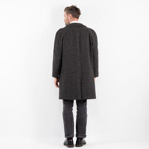 May include: A dark gray long coat with a textured pattern. The coat has a collar and long sleeves.