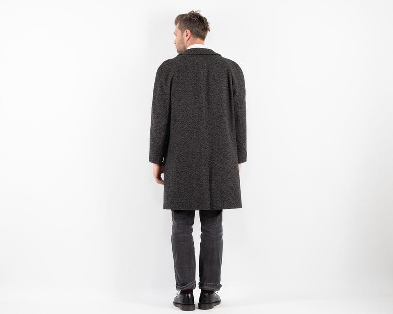 May include: A dark gray long coat with a textured pattern. The coat has a collar and long sleeves.