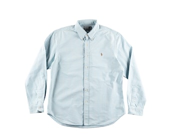 May include: A light blue and white checkered button-down shirt with long sleeves. The shirt has a button-down collar and a small brown logo on the chest. The shirt is made of a lightweight fabric.