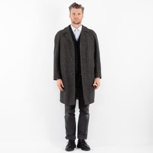 May include: A dark gray wool coat with a black button closure and a white collared shirt underneath.