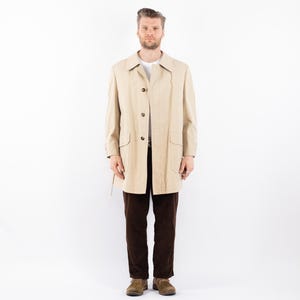 May include: A beige trench coat with a button closure and a belt. The coat has a classic design and is made of a lightweight fabric.