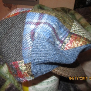 May include: A patchwork cap made of different colored fabrics, including blue, brown, red, and green. The cap has a flat brim and a slightly rounded crown.